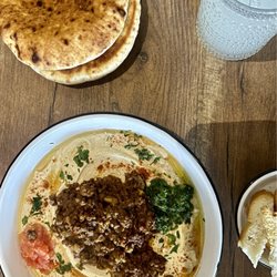KooLuLu - Jerusalem Hummus: Homemade hummus, tahini, pulled kebab, grated tomato, schug, parsley, olive oil.