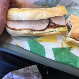 a person holding a sandwich with ham and egg a person holding a sandwich with ham and egg