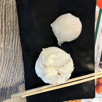 IT DIMSUM - Shrimp and Medium Steamed BBQ Pork Bun - Two steamed buns are placed on a black square plate, one with a smooth, shiny surface and the other with a fluffy, textured appearance, with chopsticks resting on the plate. - Dim Sum Near Me - Albuquerque, New Mexico