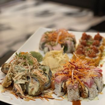 jony's sushi - Specialty rolls: big trouble in little China, hot Jony, Mr. Miyagi and I can't remember the last one! - A rectangular white plate holds an assortment of sushi rolls, including rolls topped with shredded vegetables, sauces, and seafood. The plate includes rolls with visible raw fish, fried components, and various garnishes such as shredded carrots and cabbage. Wasabi and pickled ginger are also present on the plate, set on a table with a blurred background. - Sushi Bars Near Me - Columbus, Ohio