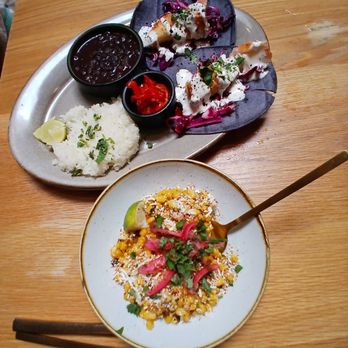 Lady Nomada - Mexican Kitchen - Incredibly delicious - A meal featuring two plates of Mexican cuisine, including rice, beans, and topped dishes with colorful garnishes, on a wooden table. - Mexican Near Me - Arvada, Colorado