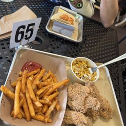 Fried chicken with fries and street corn. Shrimp tacos in the back Fried chicken with fries and street corn. Shrimp tacos in the back