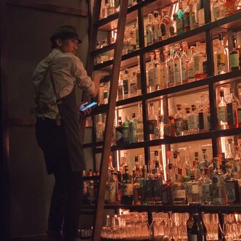 Dawn Club - The mixologist climbing ladder to retrieve a select bottle of spirits. - Cocktail Bars Near Me - San Francisco, California