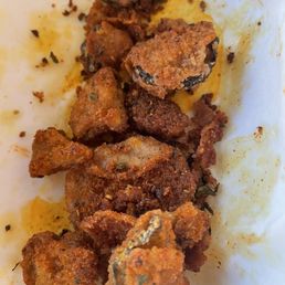 Dry Rub Wings - Fried pickle chips seasoned with dry rub are shown on a white paper surface, with some oil and seasoning remnants visible.