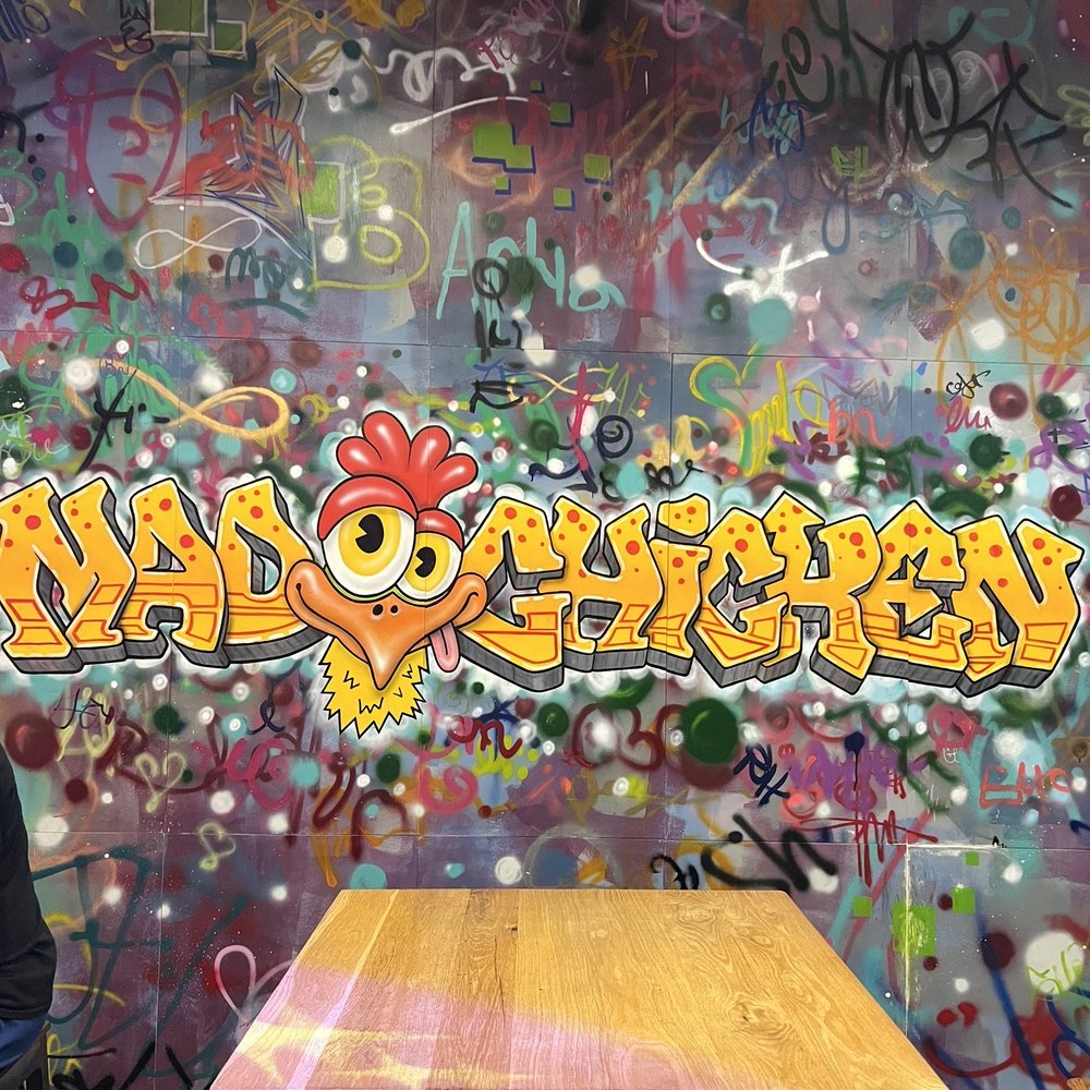 Mad Chicken - a man sitting at a table in front of a graffiti covered wall - Chicken Shop Near Me - Pittsburgh, Pennsylvania Mad Chicken - a man sitting at a table in front of a graffiti covered wall - Chicken Shop Near Me - Pittsburgh, Pennsylvania