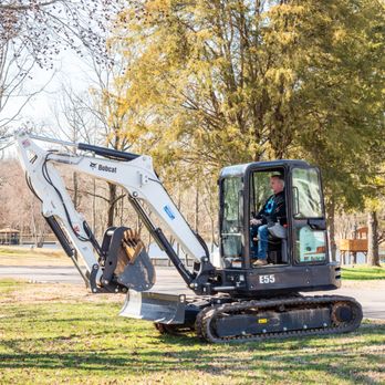 Boom Brush Control - a small excavator in a park - Tree Services Near Me
