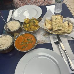 a plate of rice, a bowl of curry, and a bowl of naan bread