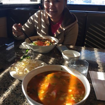 Oriental Grill - a woman sitting at a table with a bowl of soup - Vietnamese Near Me - Strathmore, Alberta