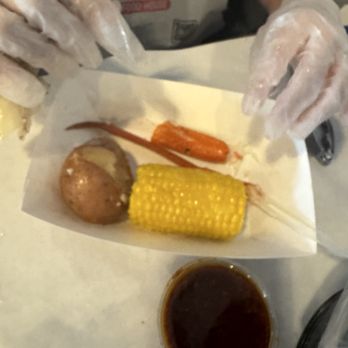 The Kickin' Crab - Here is potato corn, and some crab that my son was eating. That sauce is the mild on the side. - Seafood Near Me - Montclair, California
