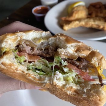 The Sloop Tavern - a hand holding a half eaten sandwich - Pubs Near Me - Seattle, Washington The Sloop Tavern - a hand holding a half eaten sandwich - Pubs Near Me - Seattle, Washington
