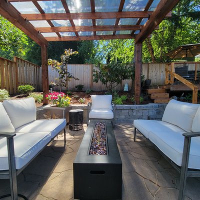 Between Two Decks: Outdoor Living in Hillsdale - Nestled in Portland's charming Hillsdale neighborhood, this small yard has been transformed into a delightful retreat with a focus on comfort and functionality.
Central to the design is a newly created covered patio, featuring a sleek polycarbonate cover that provides shelter while allowing natural light to filter through. Flanking this inviting space are two beautifully restored decks, offering additional areas for relaxation and outdoor enjoyment.
To enhance the aesthetic and practicality of the yard, we introduced a low retaining wall and carefully selected a variety of colorful plants that seamlessly blend with the homeowner's existing garden. This thoughtful integration ensures a harmonious transition between old and new, creating a vibrant and cohesive outdoor environment. Between Two Decks: Outdoor Living in Hillsdale - Nestled in Portland's charming Hillsdale neighborhood, this small yard has been transformed into a delightful retreat with a focus on comfort and functionality.
Central to the design is a newly created covered patio, featuring a sleek polycarbonate cover that provides shelter while allowing natural light to filter through. Flanking this inviting space are two beautifully restored decks, offering additional areas for relaxation and outdoor enjoyment.
To enhance the aesthetic and practicality of the yard, we introduced a low retaining wall and carefully selected a variety of colorful plants that seamlessly blend with the homeowner's existing garden. This thoughtful integration ensures a harmonious transition between old and new, creating a vibrant and cohesive outdoor environment.