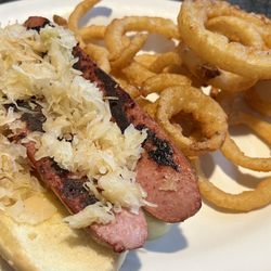 Dog 'n' Suds Restaurant - "Spicy" (not really) bratwurst with the classic Dog & Suds sauce and sauerkraut on a sesame seed bun. With crispy onion rings.