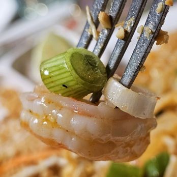 City Corner 2 - A fork holding a shrimp with pieces of onions. - Thai Near Me - Roanoke, Virginia