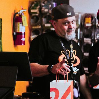 Vibe Cannabis - Smiling budtender wearing a Vibe by California hat and t-shirt behind the counter, pointing towards a Vibe shopping bag at Vibe - Cannabis Dispensaries Near Me - Moreno Valley, California Vibe Cannabis - Smiling budtender wearing a Vibe by California hat and t-shirt behind the counter, pointing towards a Vibe shopping bag at Vibe - Cannabis Dispensaries Near Me - Moreno Valley, California