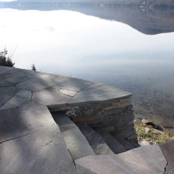 Morning Dew Landscaping & Stonework - An infinity patio atop curvilinear walls with a custom stone staircase leading you to the lake below. - Landscaping Near Me - Richmond, Vermont Morning Dew Landscaping & Stonework - An infinity patio atop curvilinear walls with a custom stone staircase leading you to the lake below. - Landscaping Near Me - Richmond, Vermont