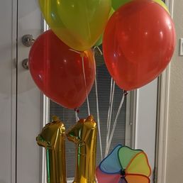 Helium balloons, a cluster of decorations with treats inside the bucket.