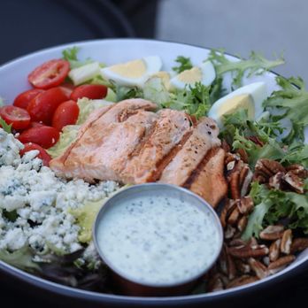 Monroe - a bowl of salad with chicken, rice, tomatoes, cucumbers, and dressing - Lounges Near Me - Hampton, Virginia