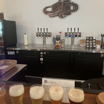 Linder Street Brewing - The bar back seen over the custom bar top, hand-crafted from repurposed church pews. - Breweries Near Me - Bowersville, Georgia Linder Street Brewing - The bar back seen over the custom bar top, hand-crafted from repurposed church pews. - Breweries Near Me - Bowersville, Georgia