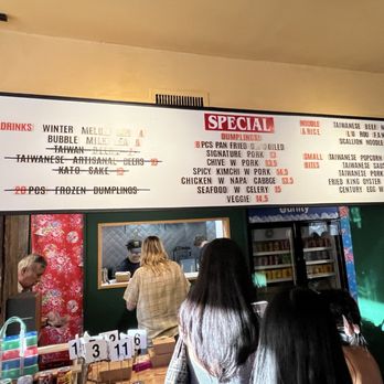Formosa - Soft launch menu - A large illuminated menu board displays food and drink options, including dumplings, noodles, small bites, and beverages, in a restaurant setting. - Taiwanese Near Me - Brooklyn, New York