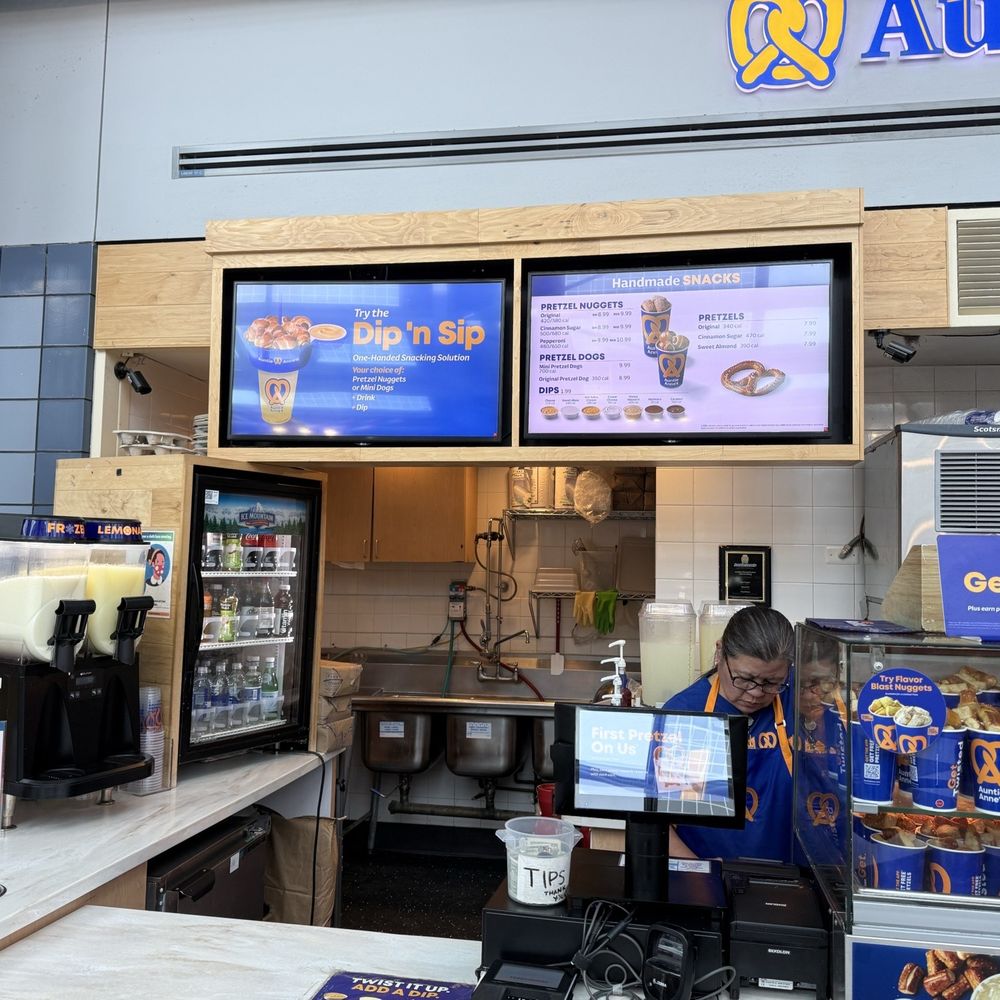 Auntie Anne's - Friendly staffer and menu board, circa Oct 2025. - Pretzels Near Me - Chicago, Illinois Auntie Anne's - Friendly staffer and menu board, circa Oct 2025. - Pretzels Near Me - Chicago, Illinois