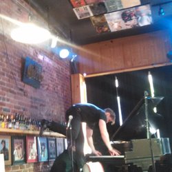 David Bennett playing the piano standing on a bass at Howiees