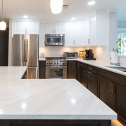 OZ General Contracting - White & wood 2-tone kitchen  L-shaped island, quartz everywhere, custom dining unit + sleek undercab & toe-kick lighting. #DreamKitchen