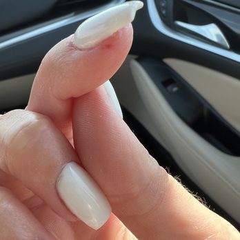 Nails World - The image features a close-up of a person's hand, focusing on the fingers with neatly manicured nails painted in white. The hand is positioned inside a car, with the vehicle's interior, including the dashboard and door panel, visible in the background. The lighting highlights the smoothness of the nails and the skin's texture. - Nail Salons Near Me - Sheboygan, Wisconsin