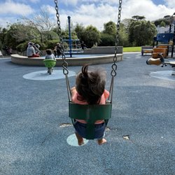 Sunnyside Recreation Center - Toddler swing area at Sunnyside Park playground with soft rubber flooring.