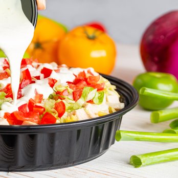 Chicken Kitchen - a person pouring dressing into a bowl of vegetables - Salad Near Me - Palmetto Bay, Florida