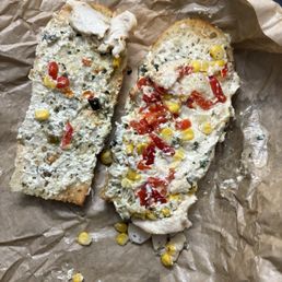 Spicy Fiesta Chicken Sandwich - Two slices of bread with chicken salad, corn, red peppers, and herbs, served on brown paper, likely from a sandwich or deli.