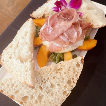 Black Forest Bistro - burrata on a bed of arugula, surrounded by peaches, topped with prosciutto and drizzled with honey - New American Near Me - Black Forest, Colorado