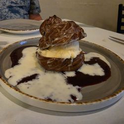 A homemade puff pastry with ice cream in the middle sitting on a raspberry coolie and white chocolate. Omg