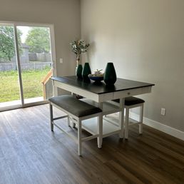 Dinning table - A rectangular dining table with a dark top and white base is positioned near a sliding glass door, with two matching benches on either side.