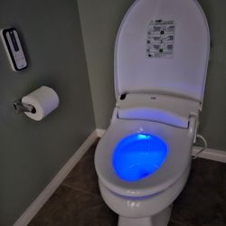 Zion Health Tech - The Smile Memory bidet on the toiletseat with the blue LED light and remote mounted on the wall.