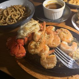 Lobster skillet, 2 lobster tails and plenty of garlic shrimp sauce on the side but don't miss it. Garlic noodles are in the bowl. Lobster skillet, 2 lobster tails and plenty of garlic shrimp sauce on the side but don't miss it. Garlic noodles are in the bowl.