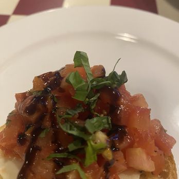 Giordano's - Bruschetta is divine - A plated dish featuring diced tomatoes, chopped green herbs, and a dark sauce, served on a white plate in a restaurant setting. - Pizza Near Me - Glen Ellyn, Illinois