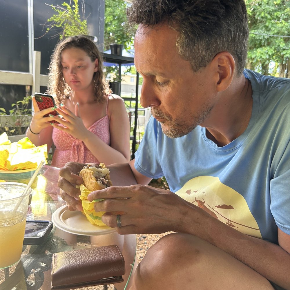 Rico Arepa - Outdoor dining area. Handsome man eating pork arepa. Lovely daughter taking a photo of her arepa! - Venezuelan Near Me - Manatí, Puerto Rico Rico Arepa - Outdoor dining area. Handsome man eating pork arepa. Lovely daughter taking a photo of her arepa! - Venezuelan Near Me - Manatí, Puerto Rico