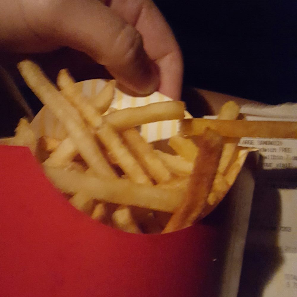 a hand reaching for french fries a hand reaching for french fries