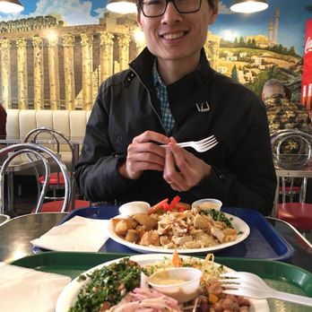 Al Balade - a man sitting at a table with plates of food - Lebanese Near Me - Quebec City, Quebec