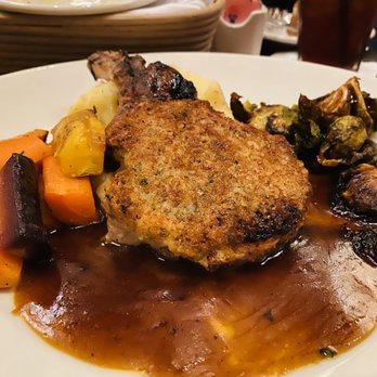 Grand Lux Cafe - Parmesan Crusted Pork Chop Thick-Cut Pork Chop Served with Mashed Potatoes, Brussels Sprouts and Roasted Carrots - American Near Me - Paramus, New Jersey