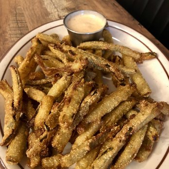 Greg's BBQ - Deep fried pickles with spice ranch - A plate of deep-fried pickles served with a small cup of spicy ranch dipping sauce, placed on a wooden table. - Barbeque Near Me - Belen, New Mexico