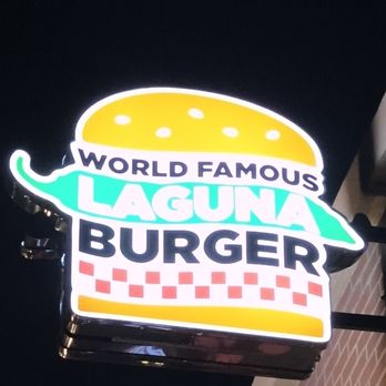 Laguna Burger - Brightly lit Laguna Burger sign displays a stylized burger graphic with a yellow bun, green outline, and red checkered pattern. The sign includes the text "World Famous Laguna Burger" in bold letters, with "Laguna" prominently in the center. The sign is mounted on a dark background, likely outside the restaurant, and is designed to attract customers with its colorful, illuminated appearance. - Burgers Near Me - Albuquerque, New Mexico