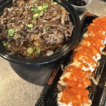 Nova Boba - A black bowl contains sliced beef garnished with chopped green onions and sesame seeds, accompanied by a sushi roll topped with orange fish roe on a black tray. - Bubble Tea Near Me - Gilbert, Arizona