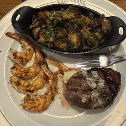 Lunch 6 ounce sirloin steak with grilled shrimp and brussels sprouts.