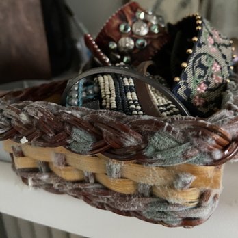 Fulton Grace Realty - Mold - A woven basket holds assorted jewelry and fabric accessories, including beaded bracelets and embroidered items. The items appear dusty or moldy, indicating they have been stored for a long time without cleaning. The basket is placed on a surface with a blurred background, possibly in a home or storage area. - Property Management Near Me - Chicago, Illinois