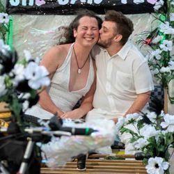 Fly By Pedal Cab - Happily and newly engaged couple kissing on pedal cab under custom made banner.
