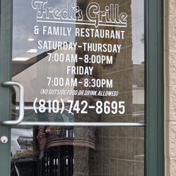 Fredi’s Grill - The front door with the phone number and hours - American Near Me - Burton, Michigan