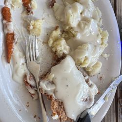 Half of the service g of chicken fried steak with mashed potatoes and extra gravy