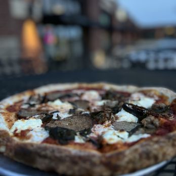 Pastaria 49 - a pizza on a plate on a table - Italian Near Me - Jonesboro, Arkansas Pastaria 49 - a pizza on a plate on a table - Italian Near Me - Jonesboro, Arkansas