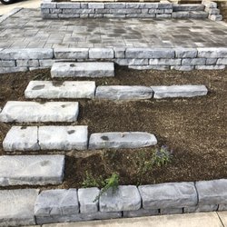 Earth Ecology - Large terraced paver patio with stone raised bed and stairs.